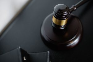 From above of wooden gavel on round surface near folders on table in courtroom